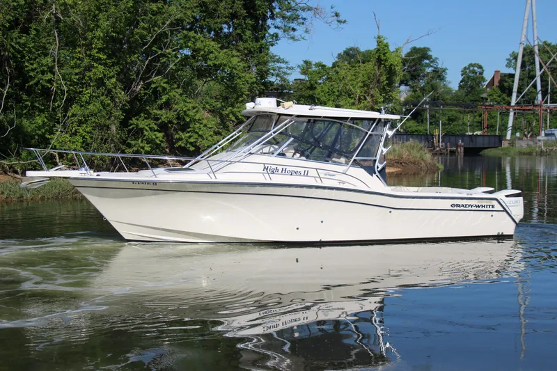 Slide: The Image of 2005 Grady-White Express 330 boat cruising on a calm river with lush greenery. - 5