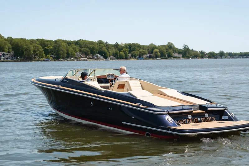 Slide: The Image of 2022 Chris Craft 34 Launch Heritage boat cruising on a lake with lush shoreline. - 1