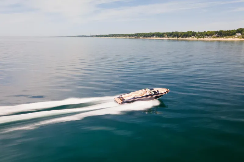 Slide: The Image of 2022 Chris Craft 34 Launch Heritage cruising on calm waters near a scenic shoreline. - 14