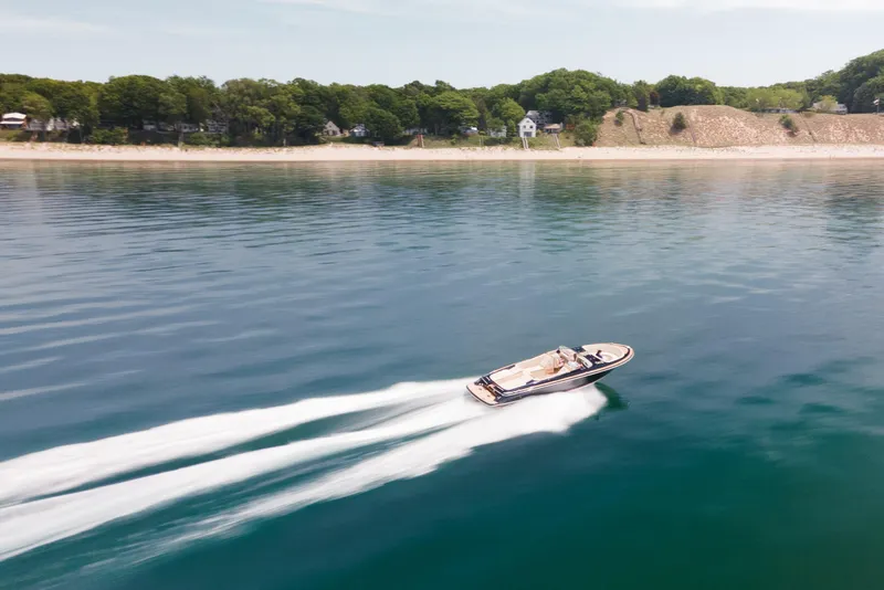 Slide: The Image of 2022 Chris Craft 34 Launch Heritage cruising on serene waters near a sandy shoreline. - 15