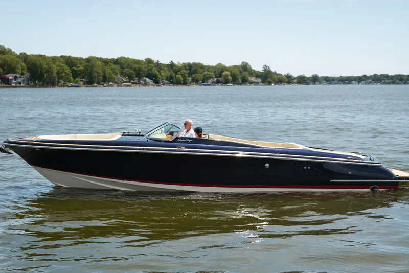 Slide: The Image of 2022 Chris Craft 34 Launch Heritage boat cruising on a serene lake. - 2