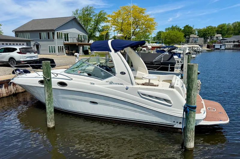 The Image of 2005 Sea Ray Sundancer 260 docked at a marina, surrounded by calm waters and scenic views. - 1