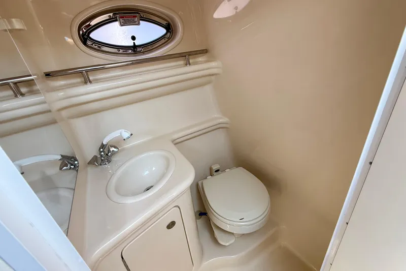 Slide: The Image of 2005 Sea Ray Sundancer 260 bathroom with sink, toilet, and porthole window. - 24