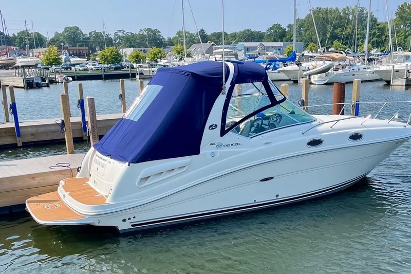 Slide: The Image of 2005 Sea Ray Sundancer 260 docked at a marina, featuring a blue canopy. - 4