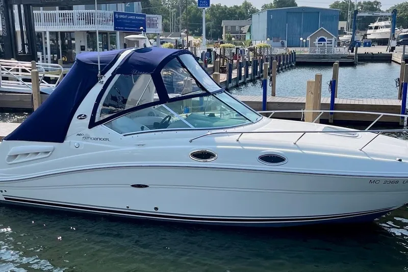 Slide: The Image of 2005 Sea Ray Sundancer 260 docked at marina, featuring sleek design and blue canopy. - 5