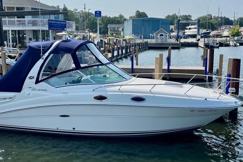 Slide: The Image of 2005 Sea Ray Sundancer 260 docked at marina, featuring sleek design and blue canopy. - 6