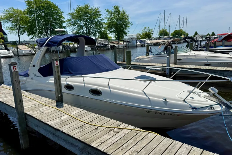 Slide: The Image of 2005 Sea Ray Sundancer 260 docked at marina, featuring blue canopy and sleek design. - 7