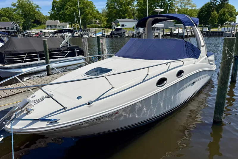Slide: The Image of 2005 Sea Ray Sundancer 260 docked at a marina, featuring sleek design and blue canopy. - 9