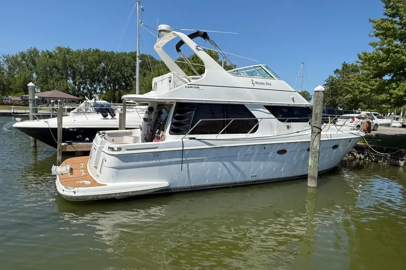 The Image of 1999 Carver 450 Voyager Pilothouse yacht docked in a marina on a sunny day. - 1