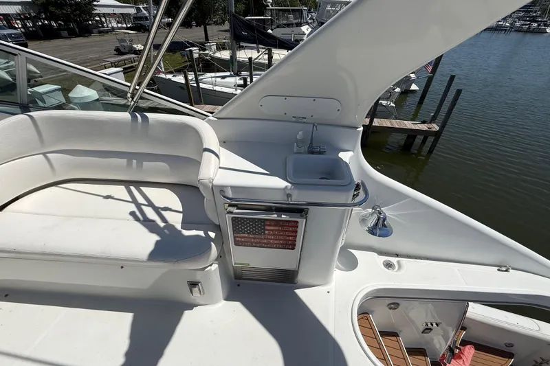 Slide: The Image of 1999 Carver 450 Voyager Pilothouse yacht deck with seating, sink, and marina view. - 12