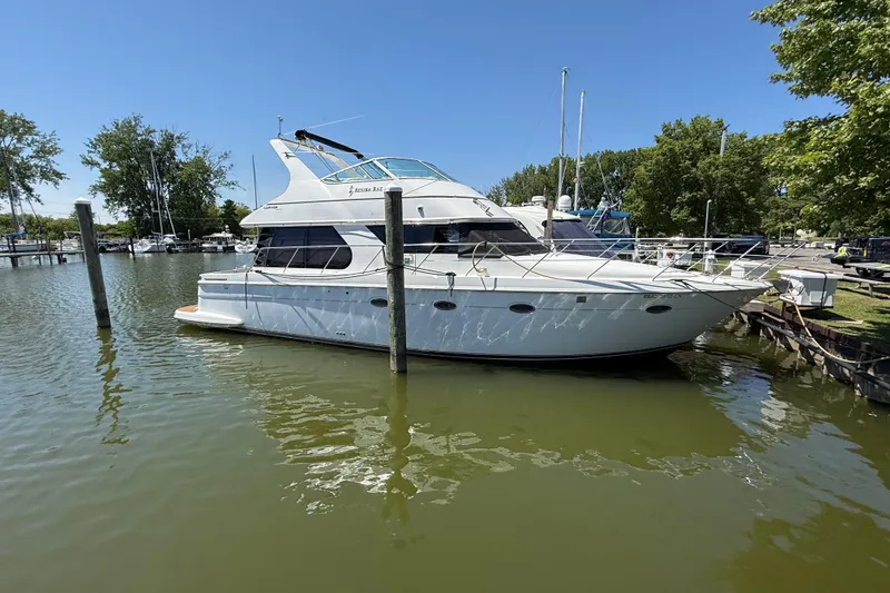 Slide: The Image of 1999 Carver 450 Voyager Pilothouse yacht docked in a serene marina setting. - 2