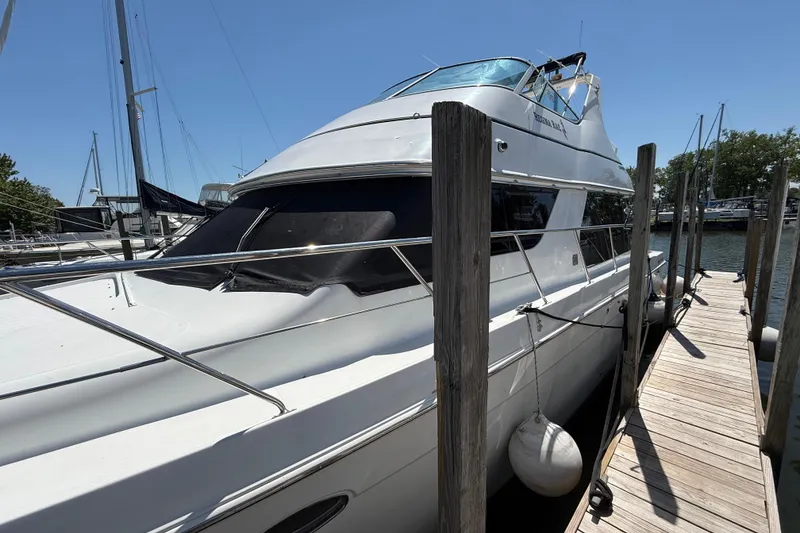 Slide: The Image of 1999 Carver 450 Voyager Pilothouse yacht docked at marina under clear blue sky. - 6