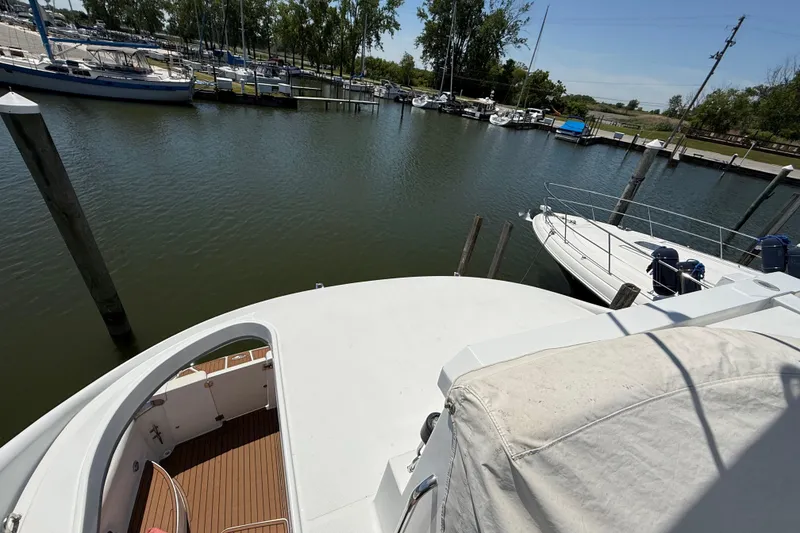 Slide: The Image of 1999 Carver 450 Voyager Pilothouse docked in a serene marina setting. - 7