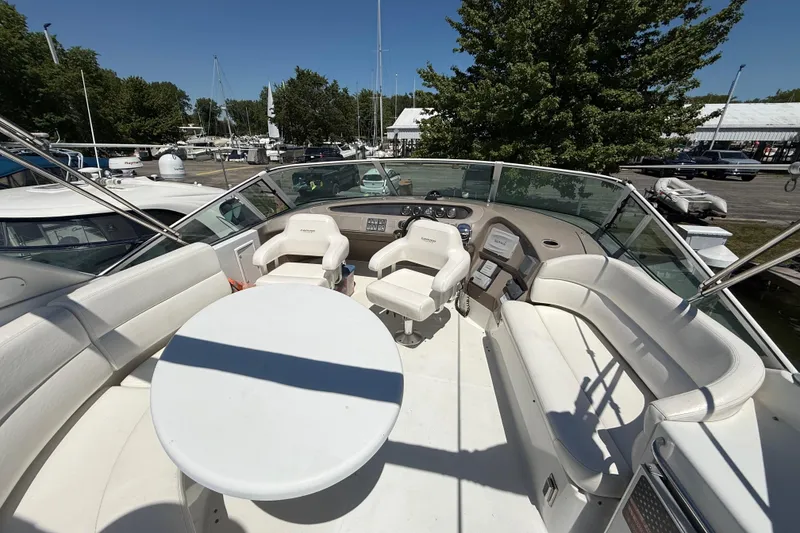 Slide: The Image of 1999 Carver 450 Voyager Pilothouse yacht interior with helm, seating, and table in marina setting. - 9