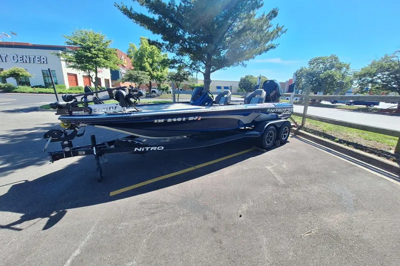 Slide: The Image of 2019 Nitro Z20 boat parked in a lot, near a building and trees. - 1