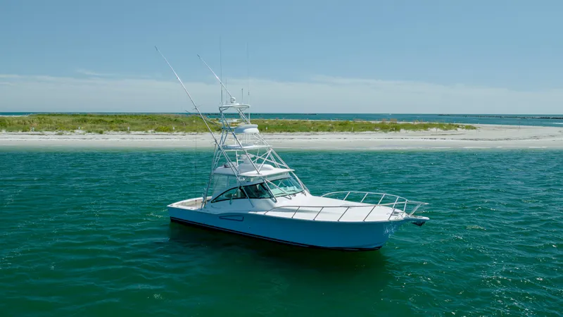 Slide: The Image of 2019 Albemarle 410 Express Fisherman boat on clear blue water near a sandy shore. - 8