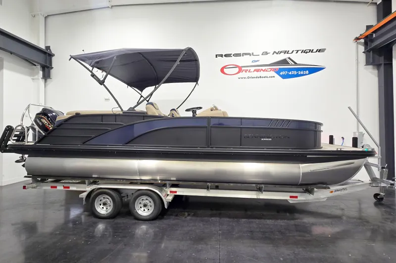The Image of 2026 Bennington 23 L pontoon boat on trailer in showroom setting. - 1
