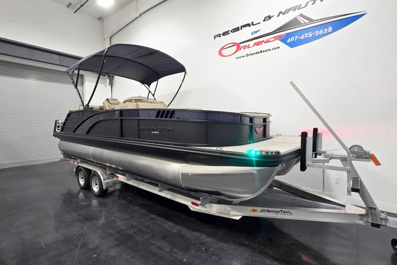 Slide: The Image of 2026 Bennington 23 L pontoon boat on trailer in showroom, featuring sleek design and canopy. - 2