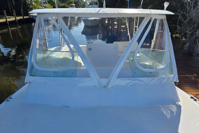 Slide: The Image of 1990 Topaz 39 Royale boat docked, featuring a white cabin and clear windows. - 4