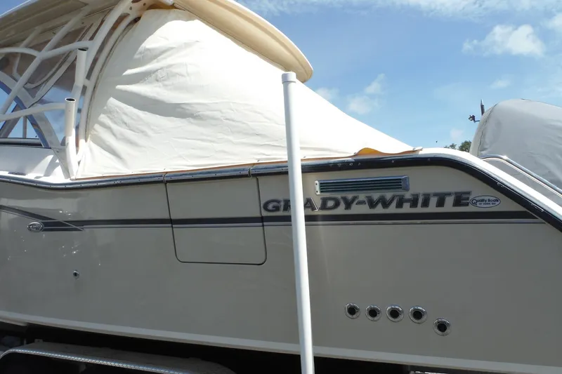 Slide: The Image of 2019 Grady-White Freedom 325 boat side view with cover, showcasing brand logo. - 14
