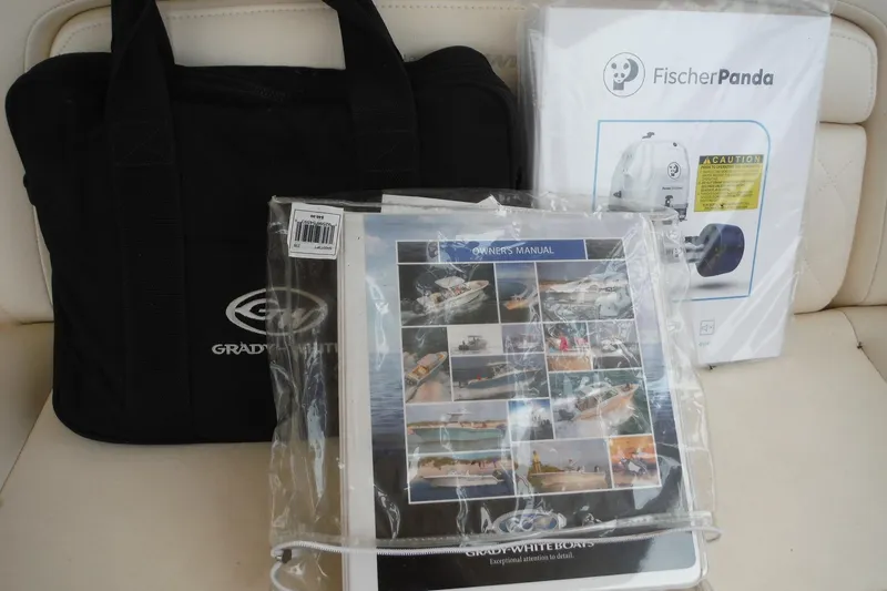 Slide: The Image of Grady-White Freedom 325 2019 owner's manual, Fischer Panda box, and branded bag on seat. - 50