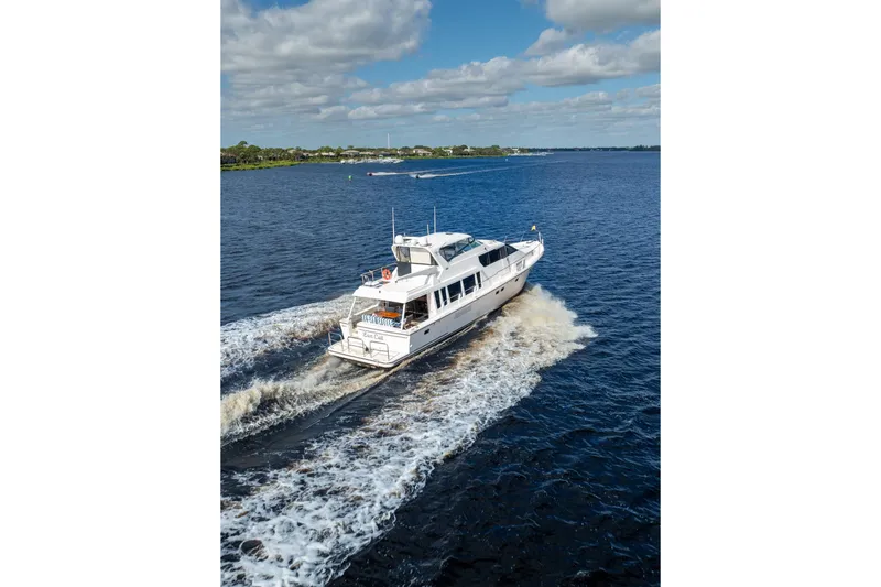 Slide: The Image of 2009 Pacific Mariner 65 Motoryacht cruising on a scenic waterway under a partly cloudy sky. - 2