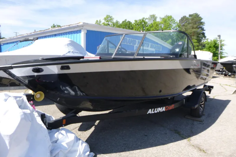 Slide: The Image of 2025 Alumacraft Trophy 175X Sport boat on trailer, parked outdoors. - 2