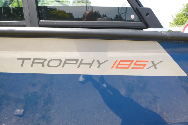 Slide: The Image of 2025 Alumacraft Trophy 185X Sport boat logo on blue exterior. - 18