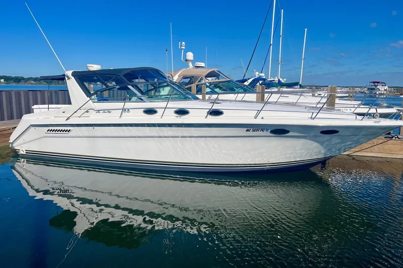 The Image of 1994 Sea Ray 370 Express Cruiser docked at marina, reflecting on calm water. - 0
