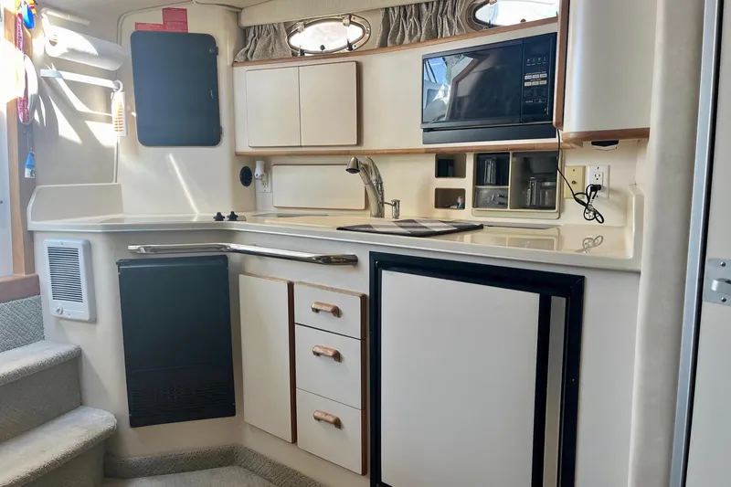 Slide: The Image of 1994 Sea Ray 370 Express Cruiser kitchen with microwave, sink, and storage cabinets. - 21