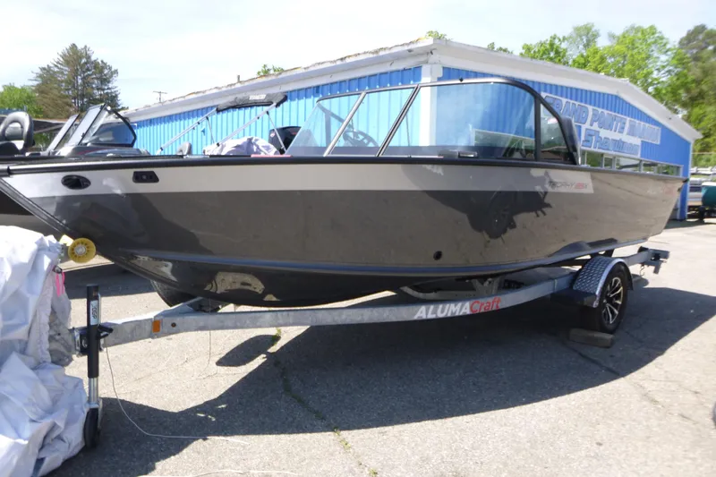 The Image of 2025 Alumacraft Trophy 185X Sport boat on trailer, parked outdoors. - 1
