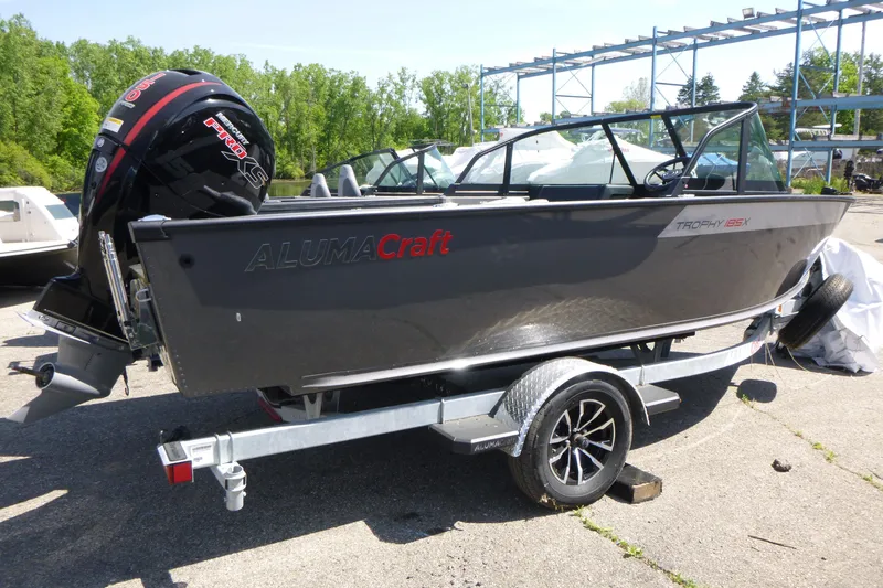Slide: The Image of 2025 Alumacraft Trophy 185X Sport boat on trailer, outdoors in sunny setting. - 3