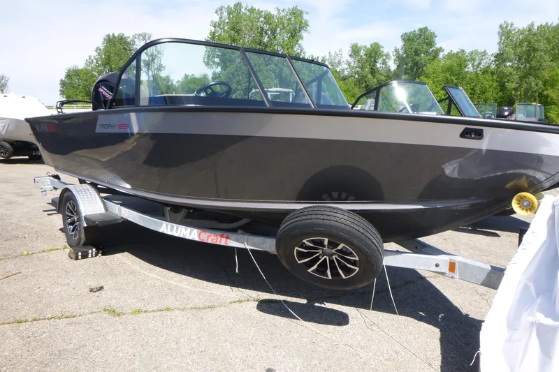Slide: The Image of 2025 Alumacraft Trophy 185X Sport boat on trailer, parked outdoors. - 4