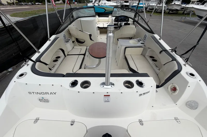 Slide: The Image of 2023 Stingray 231 DC boat interior with seating and table, docked at a marina. - 13