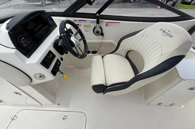 Slide: The Image of 2023 Stingray 231 DC boat cockpit with steering wheel and comfortable seating. - 20