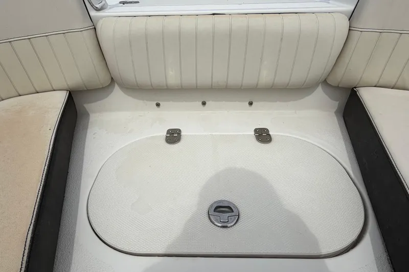 Slide: The Image of 2023 Stingray 231 DC boat interior with white cushioned seating and storage compartment. - 36