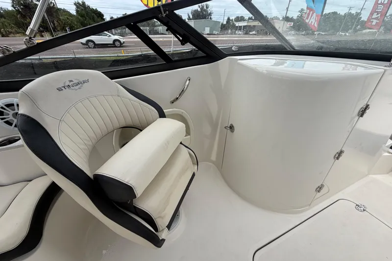 Slide: The Image of 2023 Stingray 231 DC boat interior with cushioned seating and storage compartment. - 47