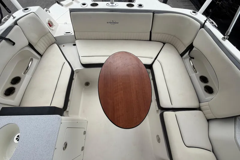 Slide: The Image of 2023 Stingray 231 DC boat interior with cushioned seating and wooden table. - 54