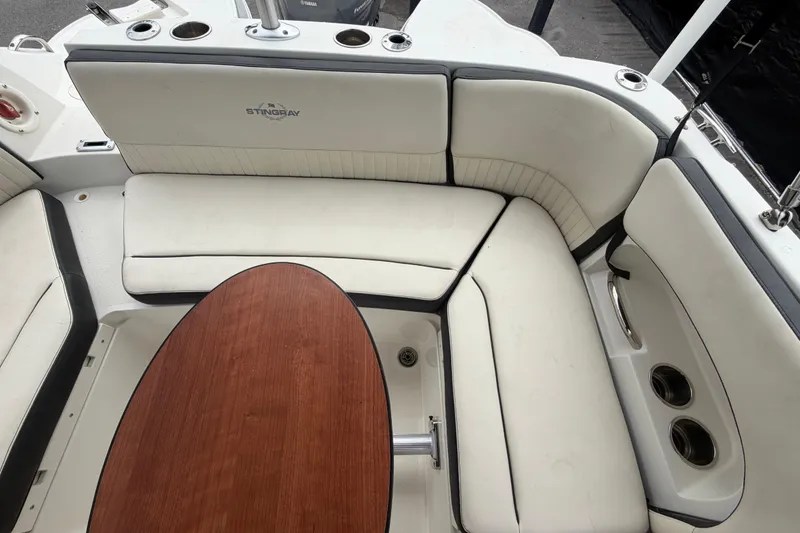 Slide: The Image of 2023 Stingray 231 DC boat interior with white seating and wooden table. - 55