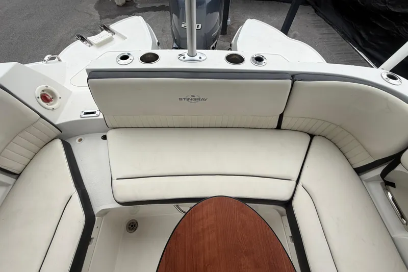 Slide: The Image of 2023 Stingray 231 DC boat interior with white seating and wooden table. - 60