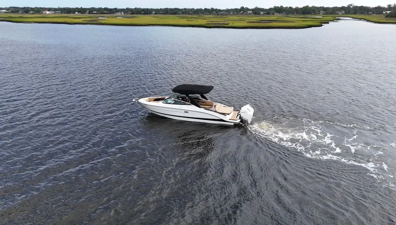 Slide: The Image of A 2027 Sea Ray SLX 280 Outboard cruising on calm waters with a green shoreline. - 9