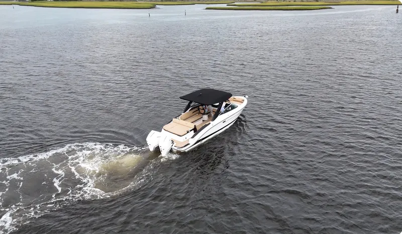 Slide: The Image of A 2027 Sea Ray SLX 280 Outboard cruising on calm waters with green shores. - 12