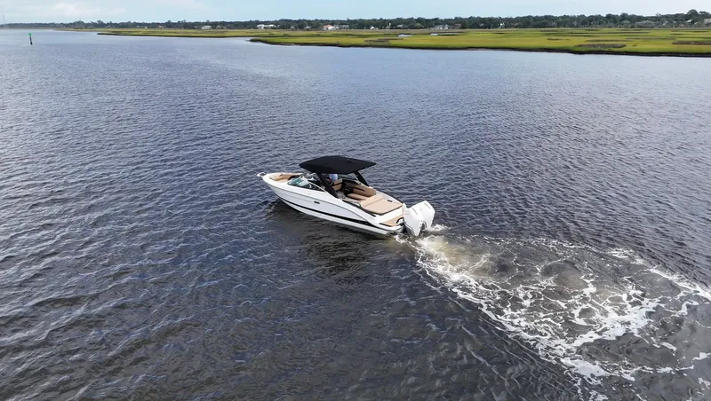 Slide: The Image of A sleek motorboat cruises on calm waters with a green shoreline in the background. - 2