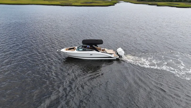 Slide: The Image of A 2027 Sea Ray SLX 280 Outboard cruising on calm waters with a green shoreline. - 8