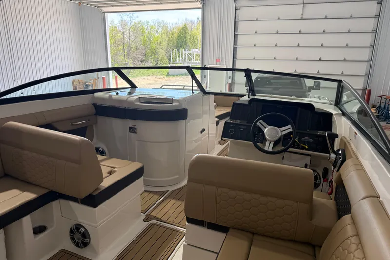 Slide: The Image of 2023 Sea Ray SDX 290 boat interior with tan seating and modern dashboard in a garage. - 3