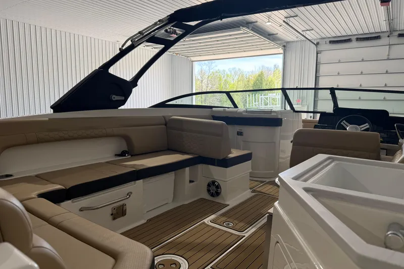 Slide: The Image of 2023 Sea Ray SDX 290 boat interior with beige seating and wood flooring in a garage. - 4