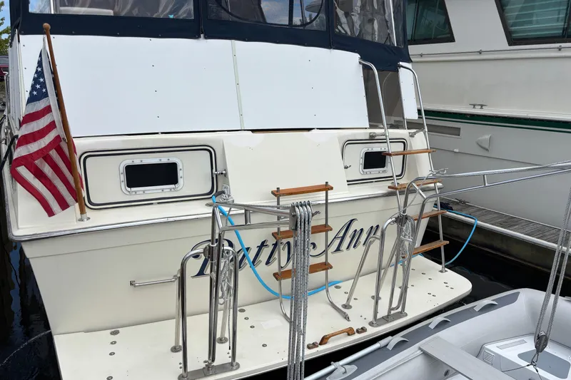 Slide: The Image of 1987 Chris-Craft 427 Catalina yacht docked, featuring American flag and boarding ladder. - 11