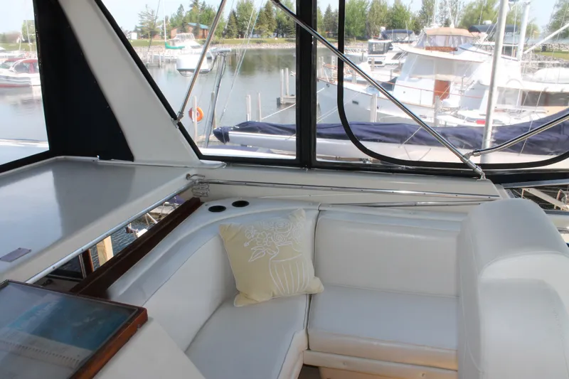 Slide: The Image of 1987 Chris-Craft 427 Catalina interior with white seating, marina view through windows. - 19