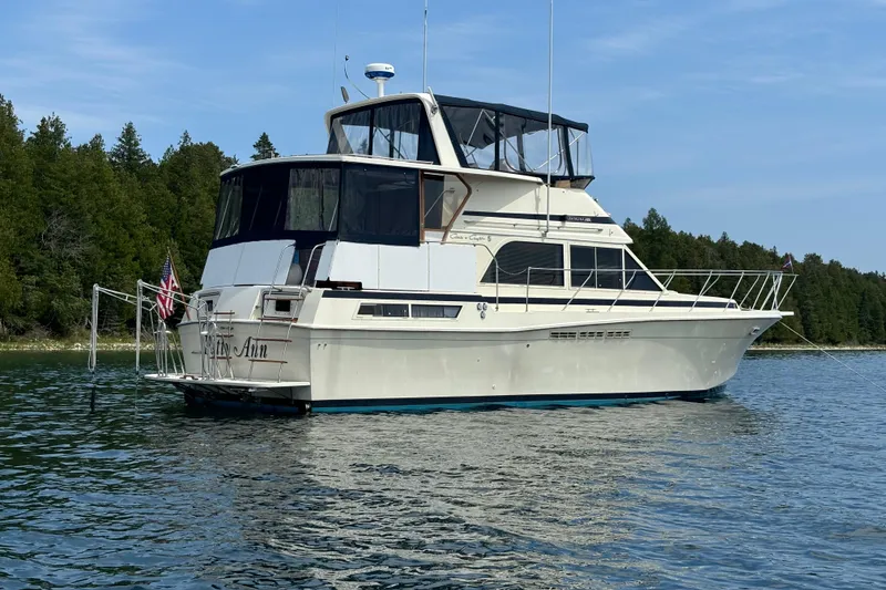 Slide: The Image of 1987 Chris-Craft 427 Catalina yacht anchored on a serene lake with forested shoreline. - 2