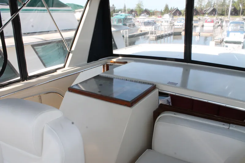 Slide: The Image of Interior view of 1987 Chris-Craft 427 Catalina yacht with white seating and marina backdrop. - 20